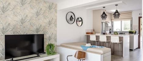 A modern kitchen with a central island, white cabinetry, and pendant lighting.