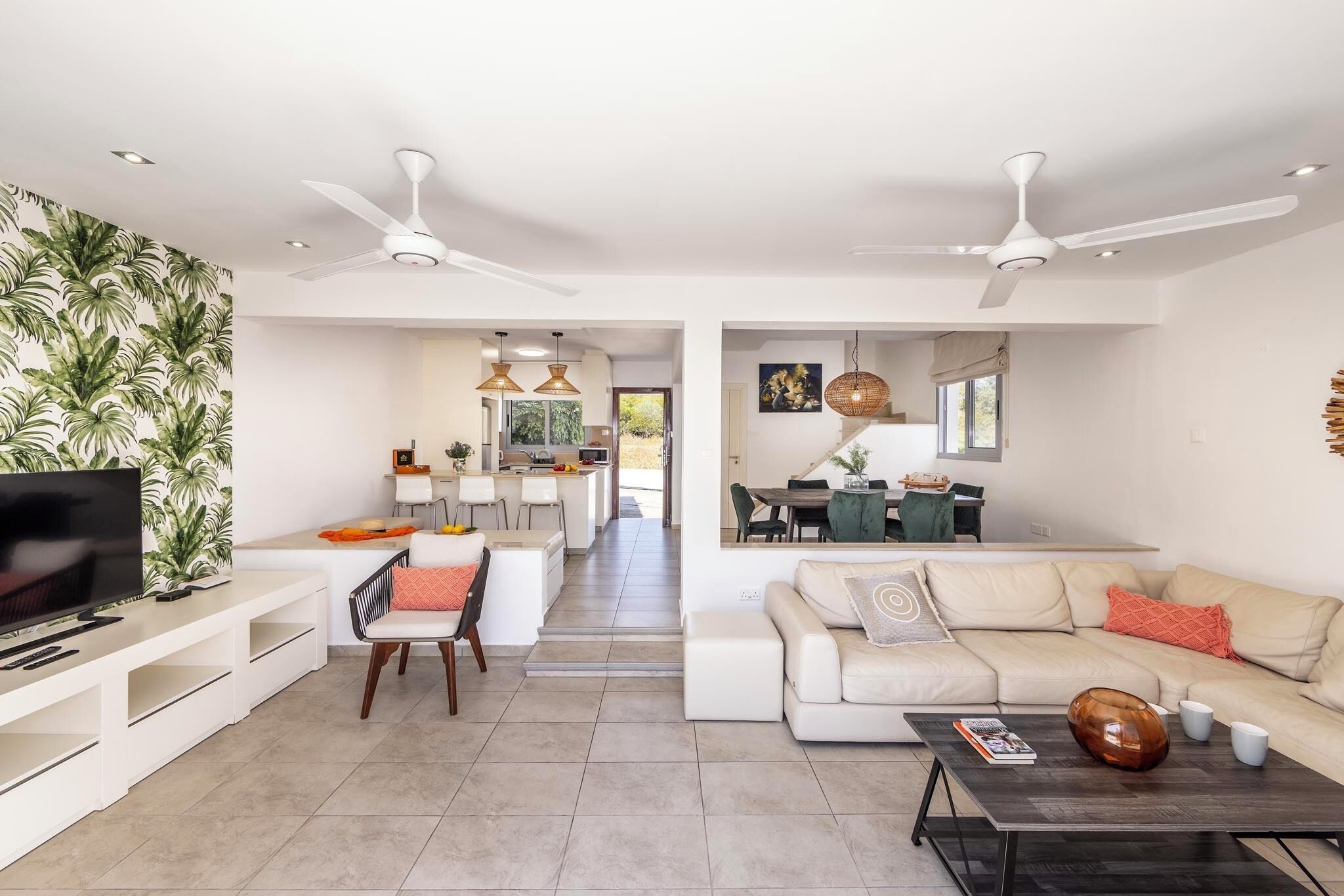 A modern living room with a TV, sofa, coffee table, and dining area.