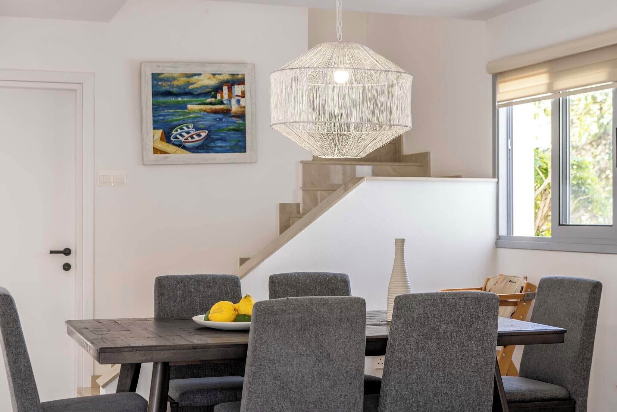 En matplats med ett bord, stolar och en hängande lampa.