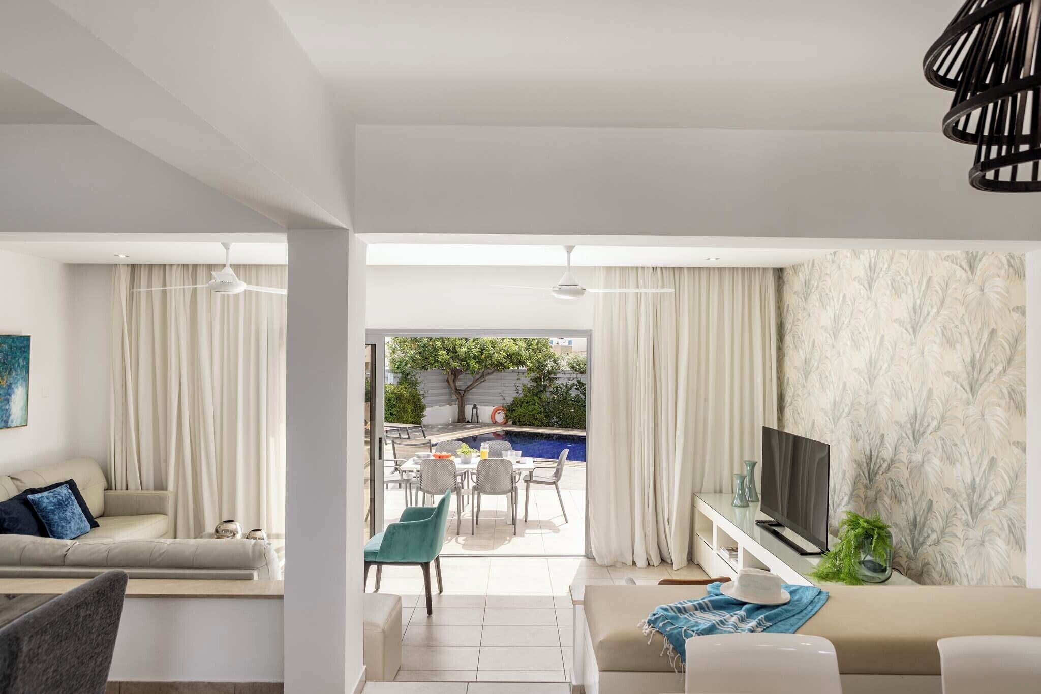 Ein modernes Wohnzimmer mit Sofa, Fernseher und Essbereich.