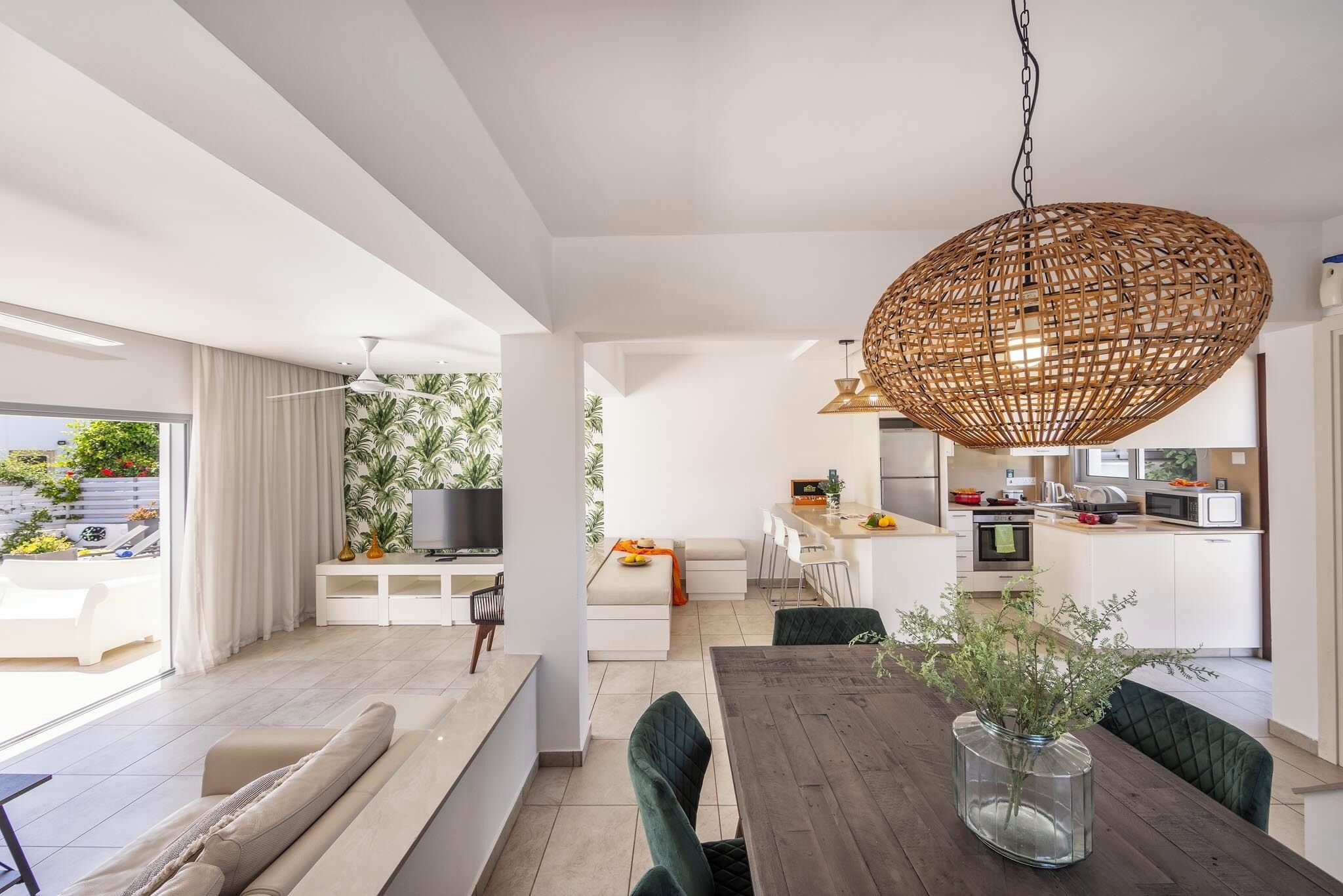 A modern living space with a dining area, kitchen, and a balcony with plants.