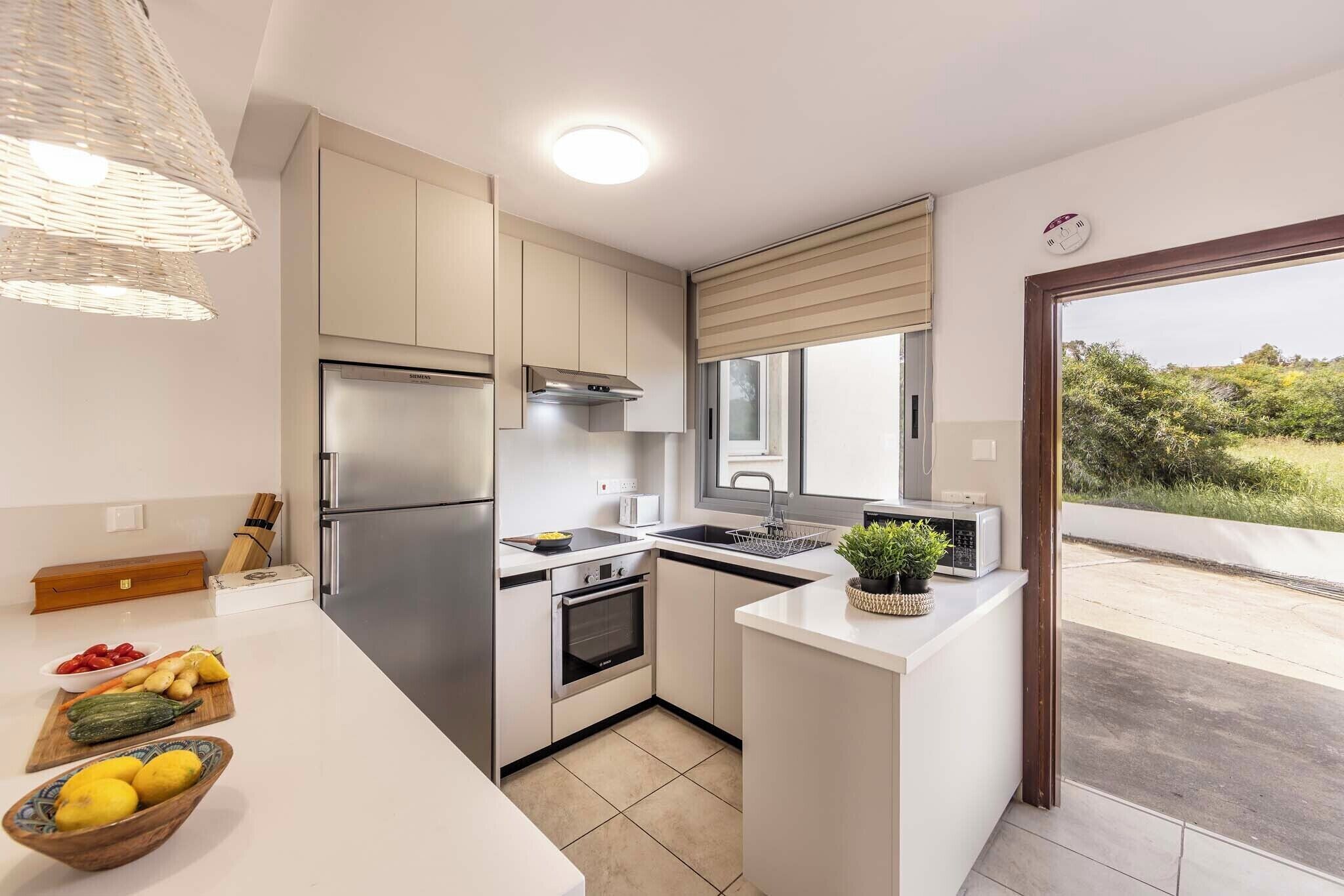 A modern kitchen with a built-in oven, stainless steel appliances, and a large window.