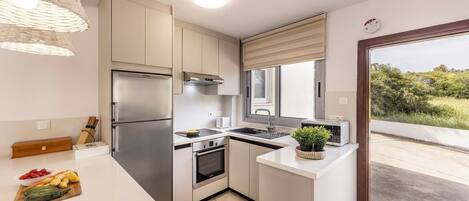 A modern kitchen with a built-in oven, stainless steel appliances, and a large window.