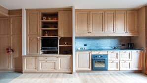 Een keuken met houten kastjes, een ingebouwde oven en een aanrecht met een waterkoker.