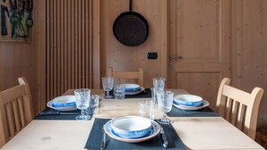 Een houten eettafel gedekt met borden, glazen en bestek.