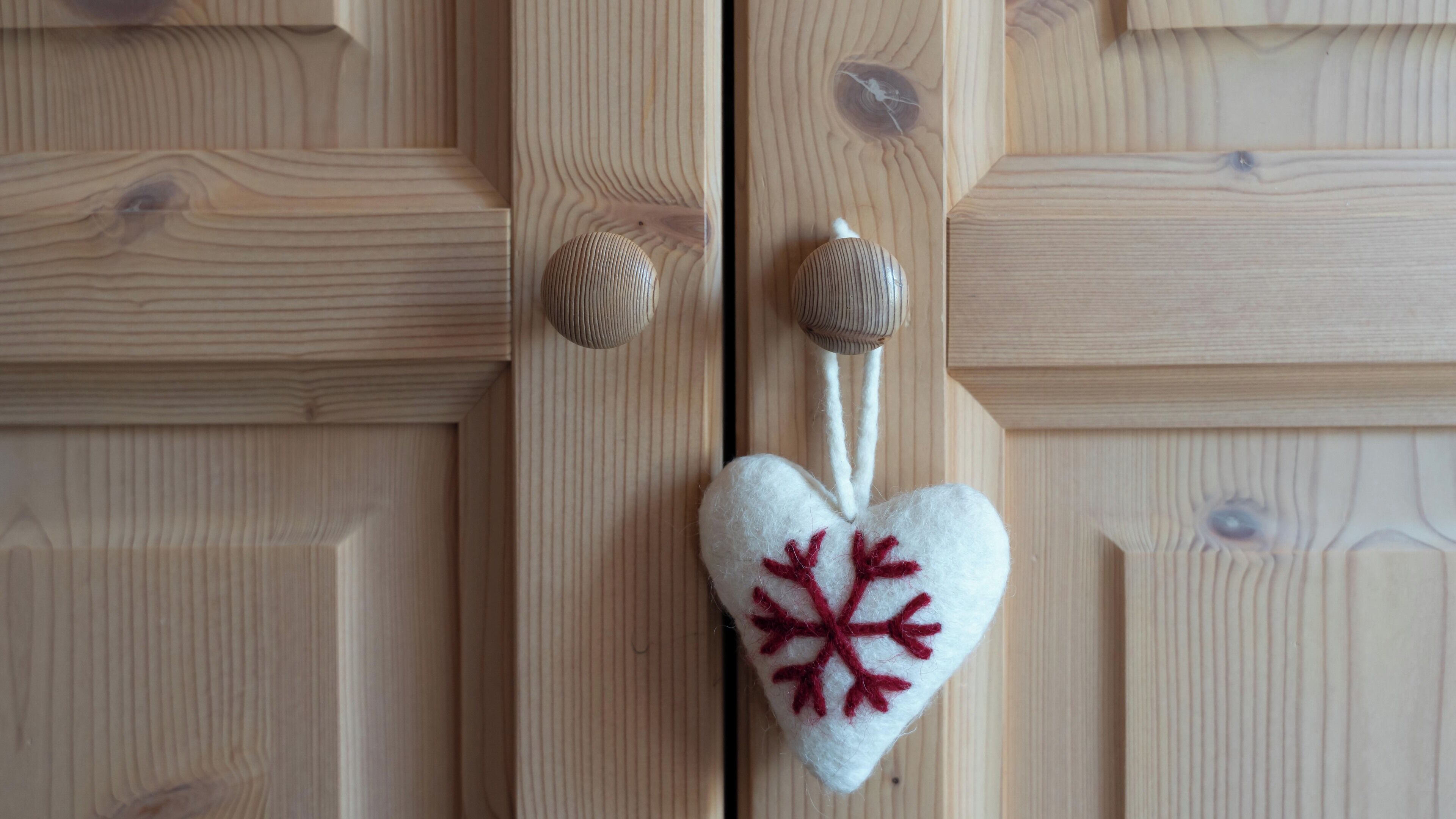 A wooden door with a heart-shaped decoration featuring a red snowflake.