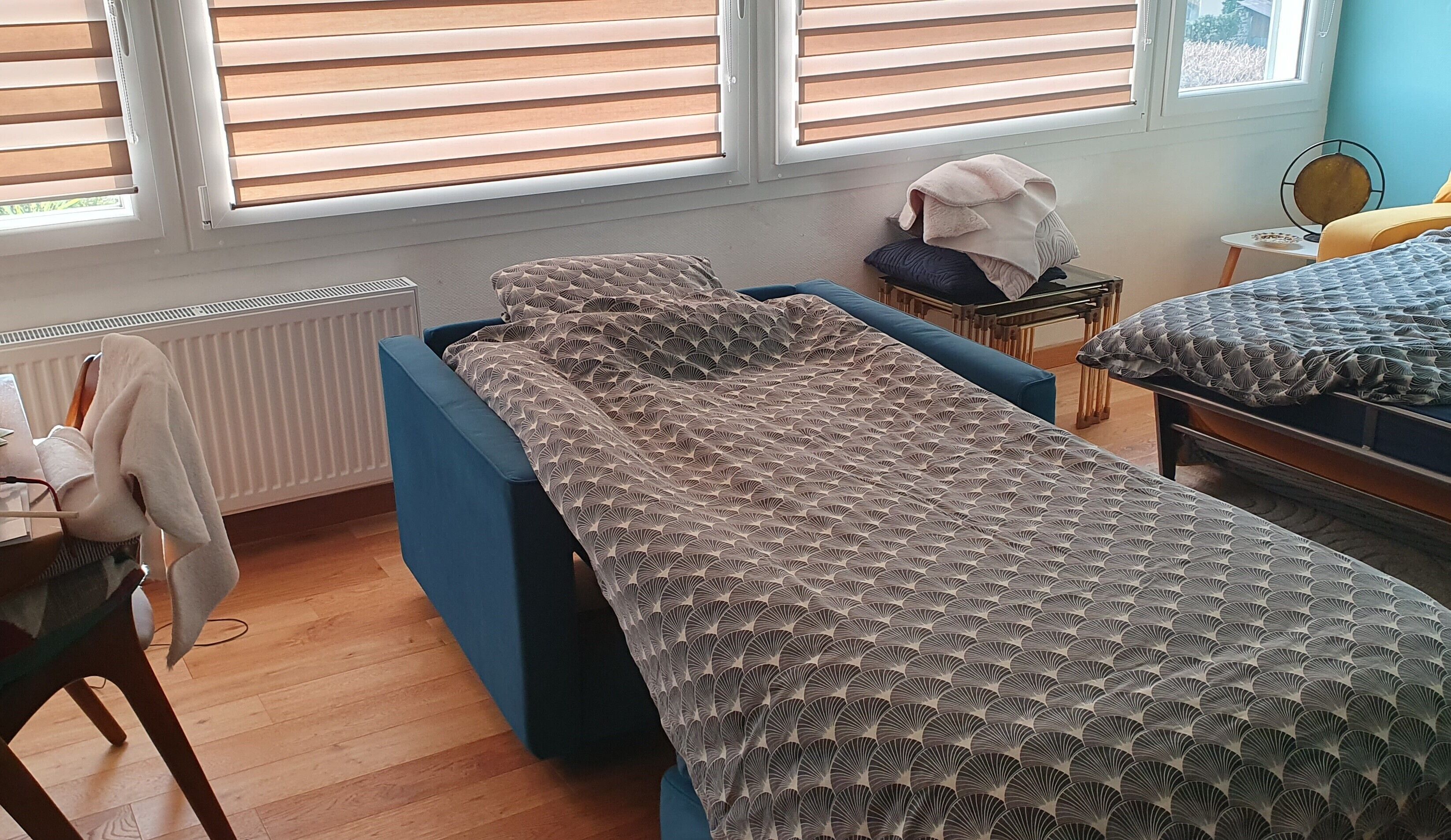 A bedroom with a single bed, a chair, a small table, and a radiator.
