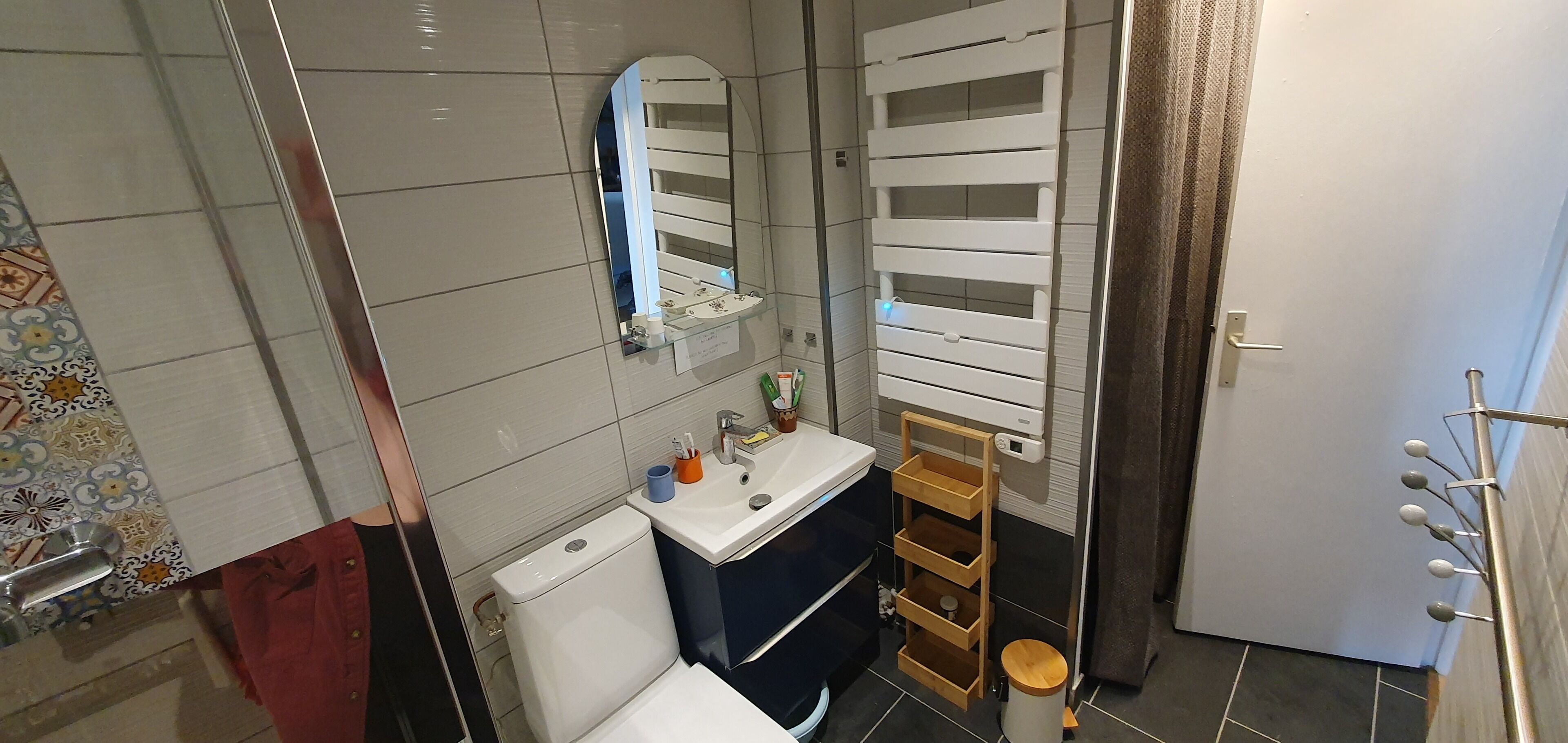 Une salle de bain équipée de toilettes, d’un lavabo, d’un miroir et d’un porte-serviettes.