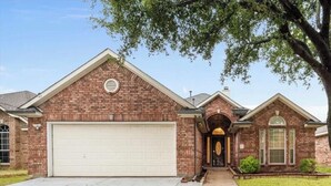 A two-story brick house with a garage, a front entrance with a decorative arch, and a small front yard. - Fantastic 3-bedroom house with AC in charming Mansfield (Mansfield)