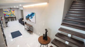 A modern interior with a staircase, a dining area, and artwork on the walls.