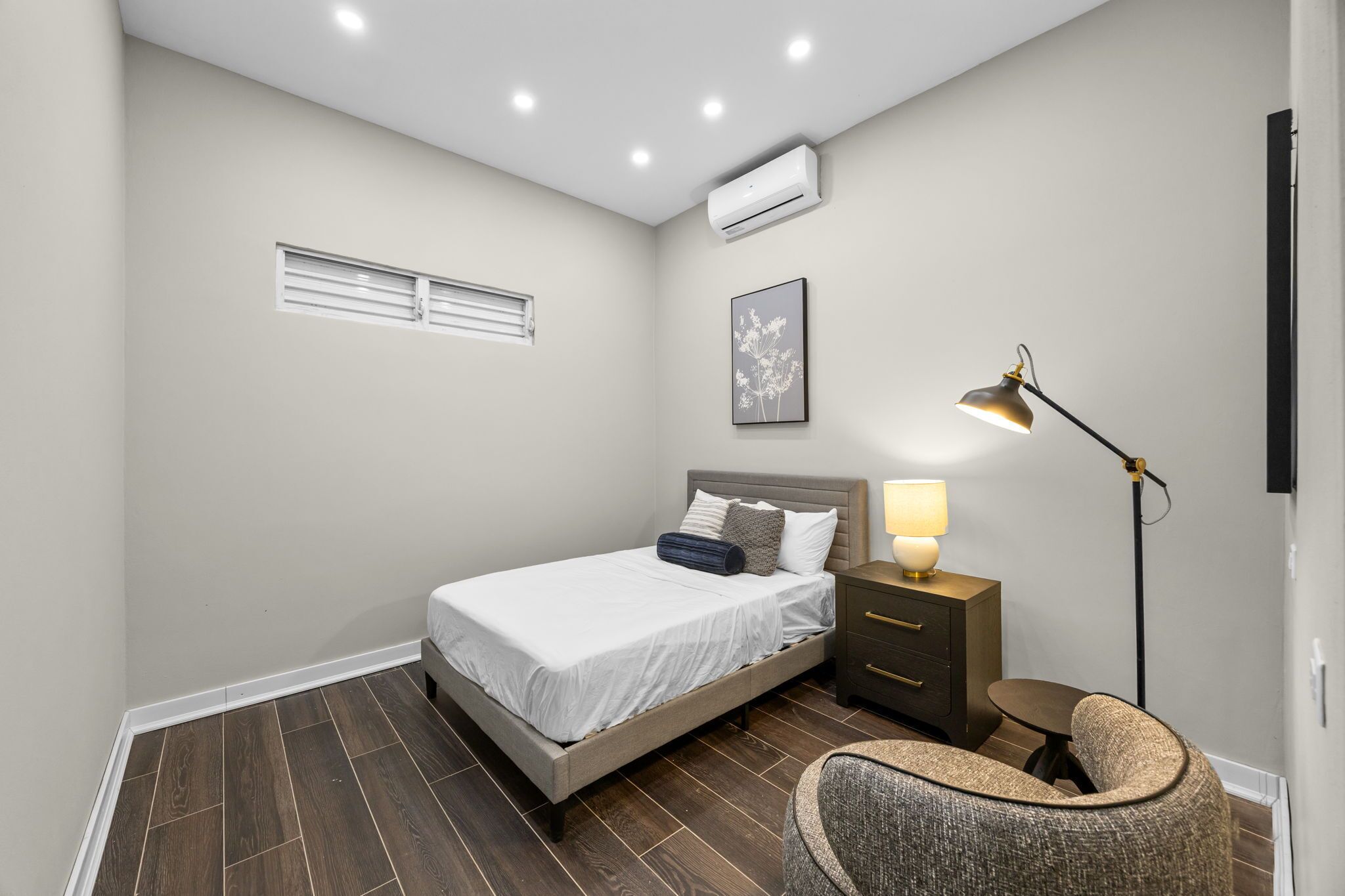 Une chambre à coucher avec un lit, une table de chevet, une lampe et une chaise.
