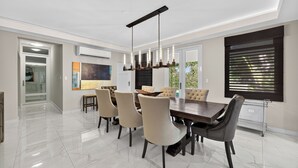 A modern dining area with a large table, six chairs, and a pendant light. - Casa Lotus (San Juan)