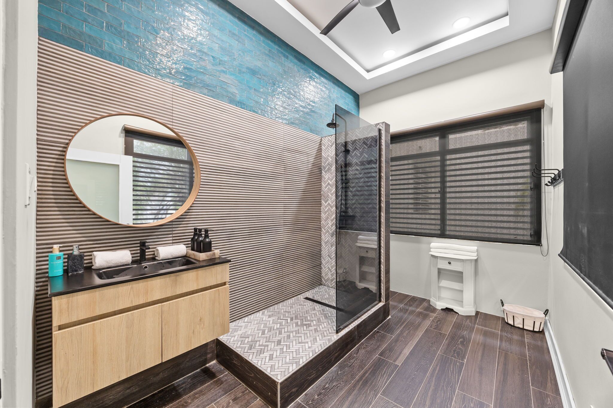 Un bagno moderno con doccia, un lavabo con specchio e una parete con motivo a spina di pesce.