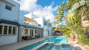 A swimming pool with a sun terrace, white walls, and tropical plants. - Casa Lotus (San Juan)