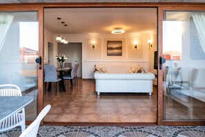 A modern living area with a white sofa, dining table, and chairs. - Villa La Perla - Cliffside Retreat (Costa de Antigua)