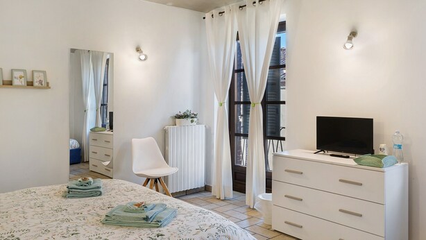 A bedroom with a bed, a TV, a dresser, a chair, and a radiator. - B&B La Rugiada with Wi-Fi (Pratomorone)