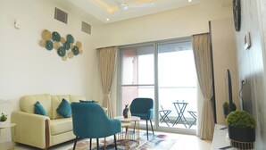 A modern living room with a sofa, two chairs, a small table, and a large window with curtains. - Auric Blue by Red Olive3bhkomrprime IT Corner (Chennai)