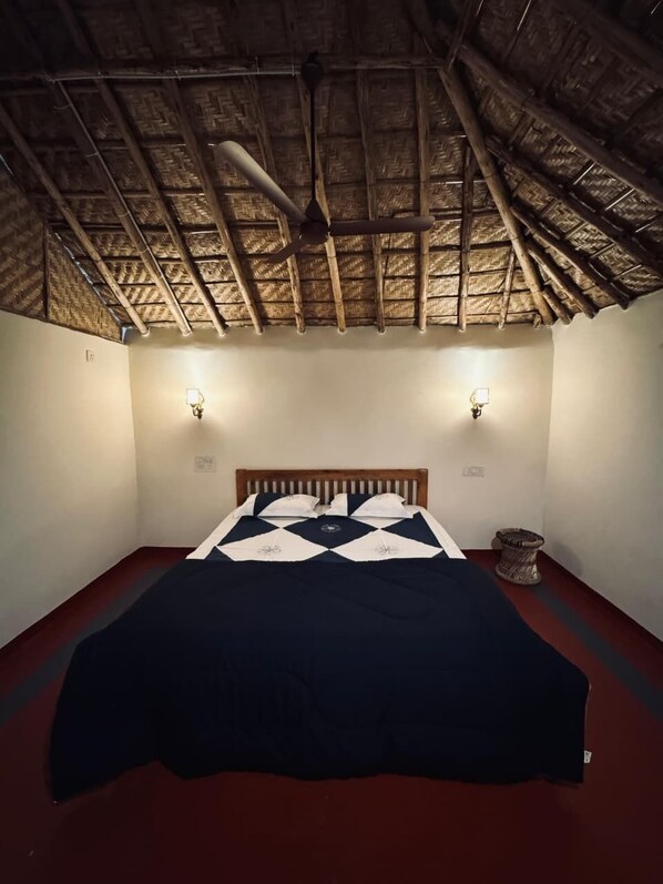A room with a bed, two wall-mounted lights, a ceiling fan, and a woven basket. - Echoes Of Hampi (Koppal)