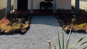 A house with a thatched roof, a front porch with two chairs, and a gravel driveway. - Echoes Of Hampi (Koppal)