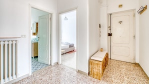 Un pasillo con un radiador, un banco y una puerta que da a un dormitorio.