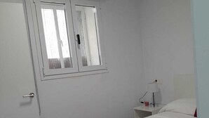 A bedroom with a bed, a nightstand, a lamp, and a window with blinds. - Central 1-Bedroom Apartment in Historic Úbeda-Aurora1 (Úbeda)