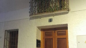 A building with a white exterior, a wooden double door, and a small balcony with metal railings. - Central 1-Bedroom Apartment in Historic Úbeda-Aurora1 (Úbeda)
