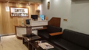 A hotel reception area with a reception desk, a black leather sofa, and a wooden reception counter. - Hotel Tulusi Inn (Bolpur)