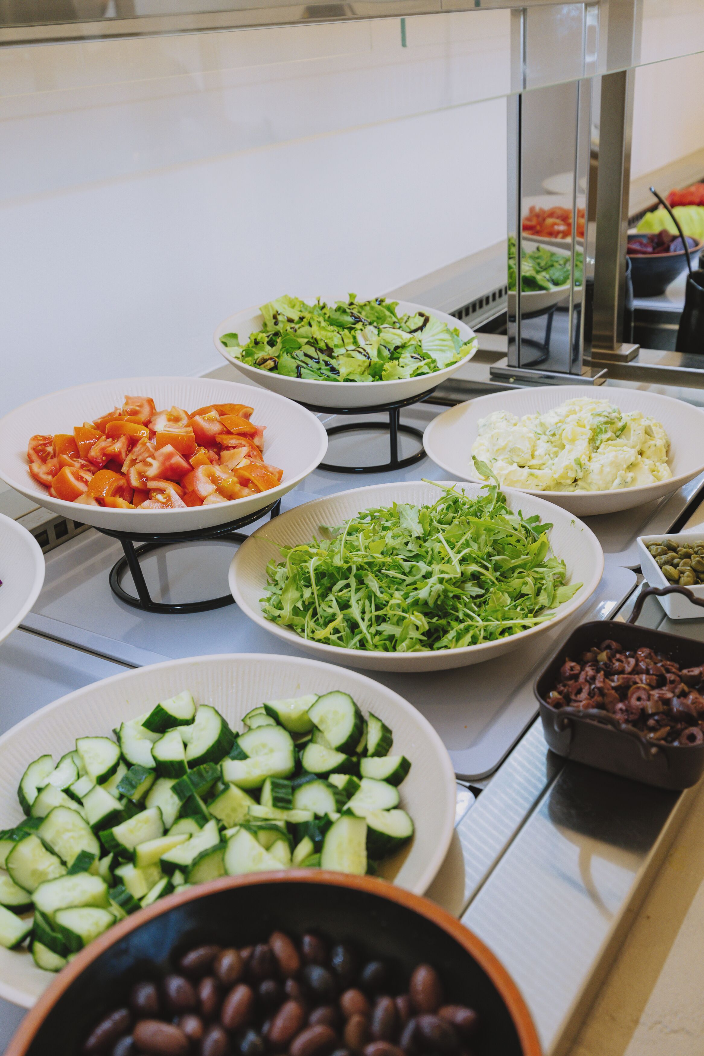 A buffet with various dishes including salads, vegetables, and beans.