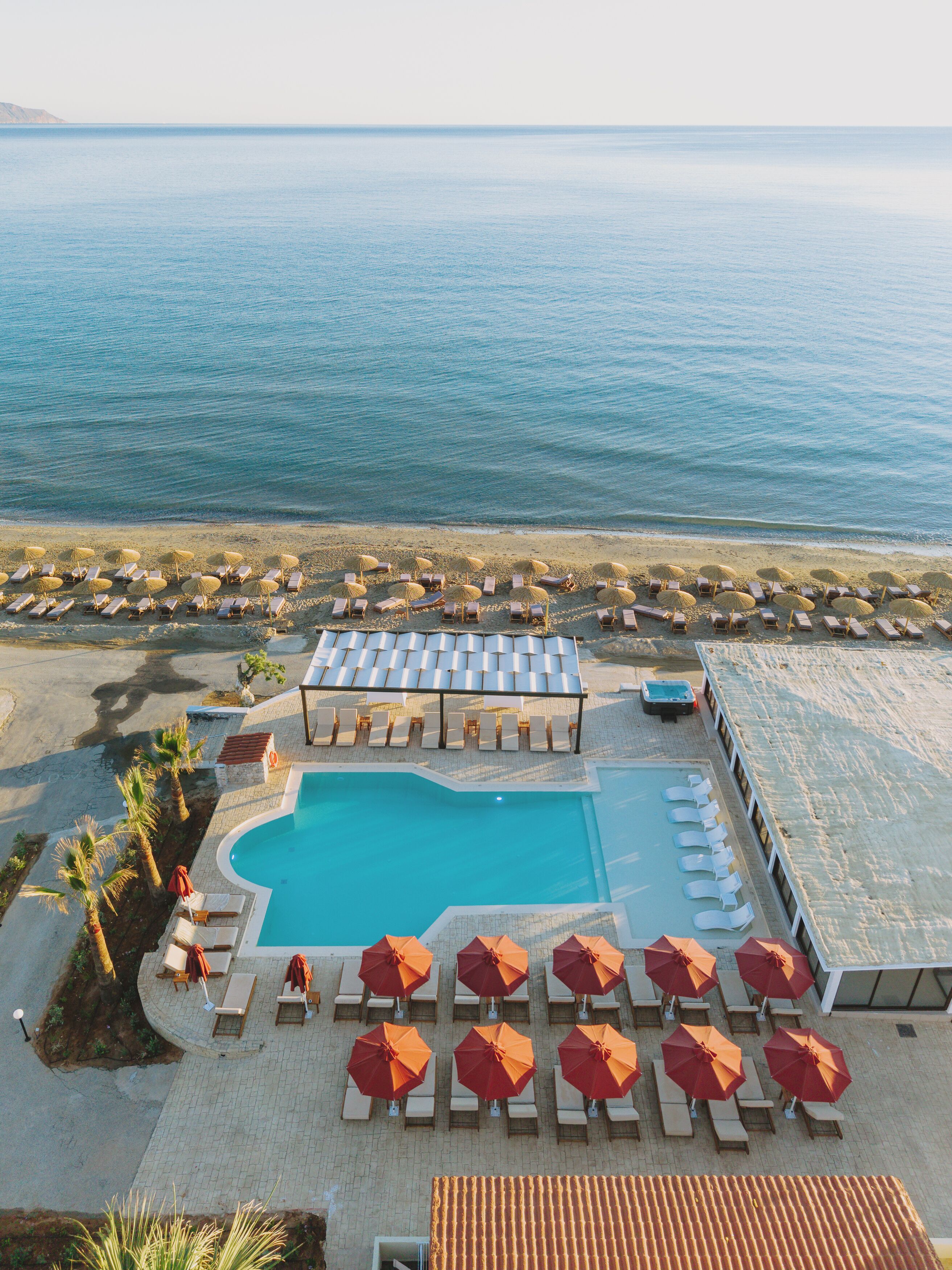 Un resort con piscina, tumbonas, sombrillas y vistas al mar.