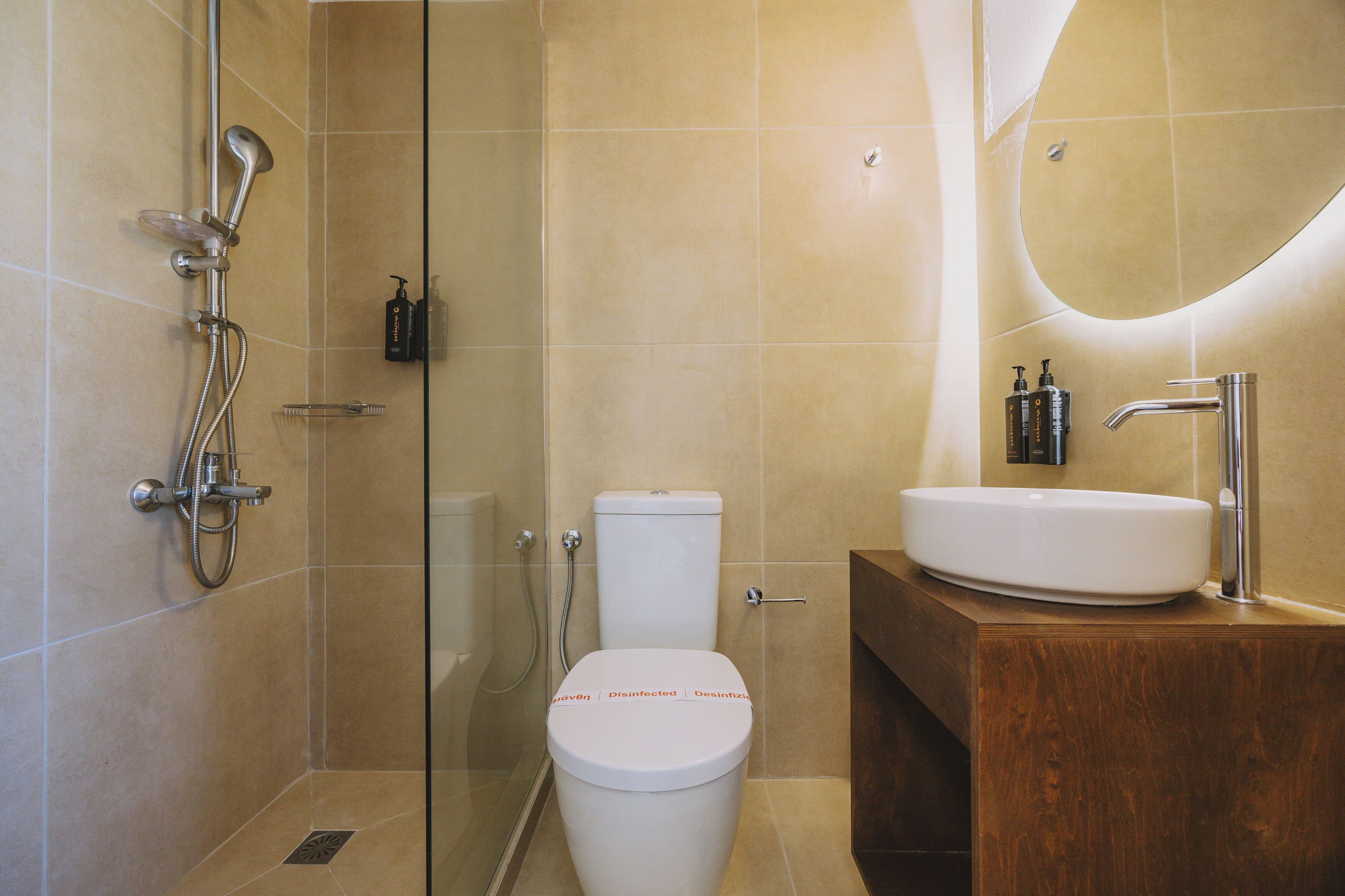 Ein modernes Badezimmer mit einer Duschkabine, einer weißen Toilette und einem Holzwaschtisch.