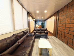 Une pièce avec un canapé en cuir marron, une table blanche et un mur décoré d’un motif en briques.