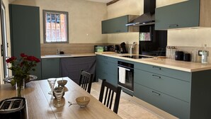 A modern kitchen with a wooden table, a sink, and a window. - Cozy Ecological Cottage in Sologne Bourbonnaise, Pets Allowed, Parking (Thiel-sur-Acolin)