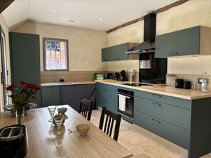 A modern kitchen with a wooden table, a sink, and a window.