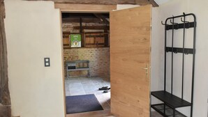 A room with a wooden door, a bench, a black metal rack, and a tiled floor. - Cozy Ecological Cottage in Sologne Bourbonnaise, Pets Allowed, Parking (Thiel-sur-Acolin)