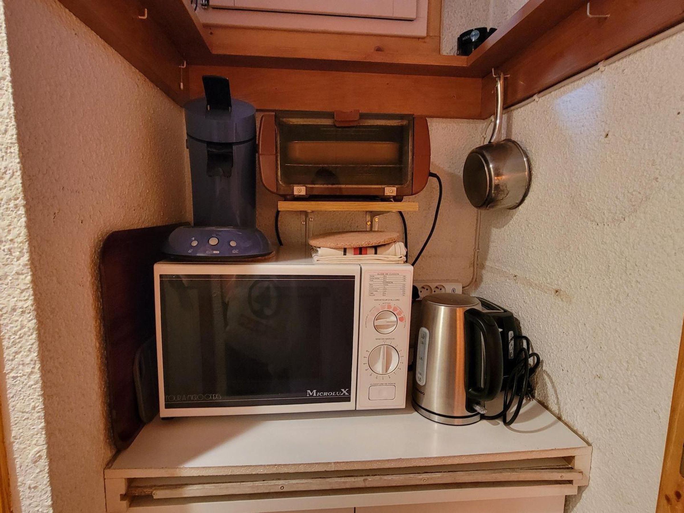A compact kitchenette with a microwave, a kettle, and a toaster.