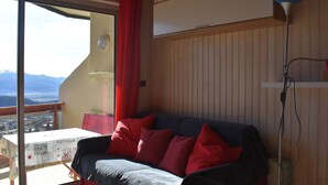 Una habitación acogedora con sofá, mesa y vistas a las montañas.