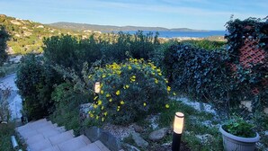 A garden with a view of the sea, stone steps, and a potted plant. - Peaceful studio with pool in Cavalaire (Cavalaire-sur-Mer)