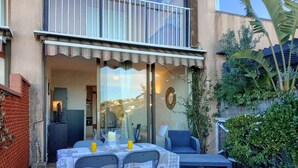 An outdoor patio with a table and chairs, a small garden, and a building entrance. - Peaceful studio with pool in Cavalaire (Cavalaire-sur-Mer)