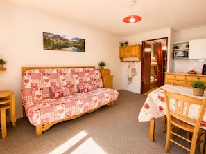 A cozy room with a wooden sofa, a dining table with chairs, a kitchen area, and a painting on the wall. - Studio for 4 at the slopes - Pets allowed (Oz)