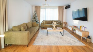Ein modernes Wohnzimmer mit Ecksofa, Couchtisch, Fernseher und Weihnachtsbaum.