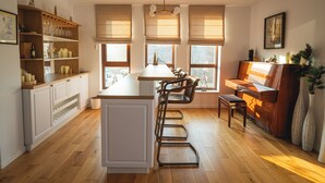 Eine Küche mit Holzboden, einer zentralen Kochinsel, Barhocker, einem Klavier und einem Fenster mit Blick.