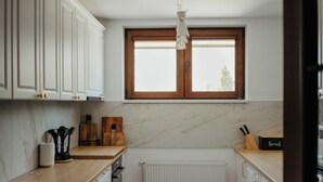 Eine Küche mit weißen Schränken, einer Holzausziehtheke, einem Fenster und einer Heizung.