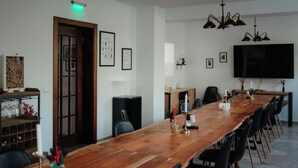 Ein langer Holztisch für Konferenzen mit schwarzen Stühlen, ein großer Flachbildfernseher an der Wand und gerahmte Bilder.
