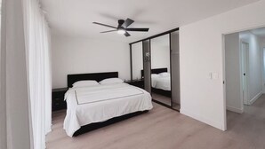 A modern bedroom with a bed, a ceiling fan, and a large mirror. - Beautiful 4-bedroom house with AC in enchanting Las Vegas (Las Vegas)