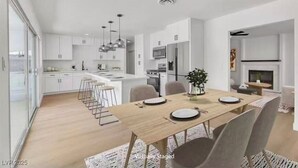 A modern kitchen with white cabinets, a wooden dining table, and bar stools. - Beautiful 4-bedroom house with AC in enchanting Las Vegas (Las Vegas)