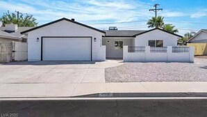 A single-story house with a garage, a small attached structure, and a fenced yard. - Beautiful 4-bedroom house with AC in enchanting Las Vegas (Las Vegas)