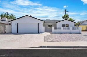 A single-story residential building with a garage, a small attached structure, and a fenced yard. - Beautiful 4-bedroom house with AC in enchanting Las Vegas (Las Vegas)