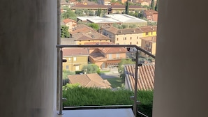 Une vue depuis un balcon, avec un ciel dégagé, une mer lointaine et un quartier résidentiel avec des maisons.