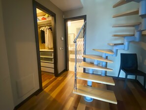 Ein modernes Interieur mit einer Holztreppe, einem Kleiderschrank mit Kleidung und einem Stuhl.