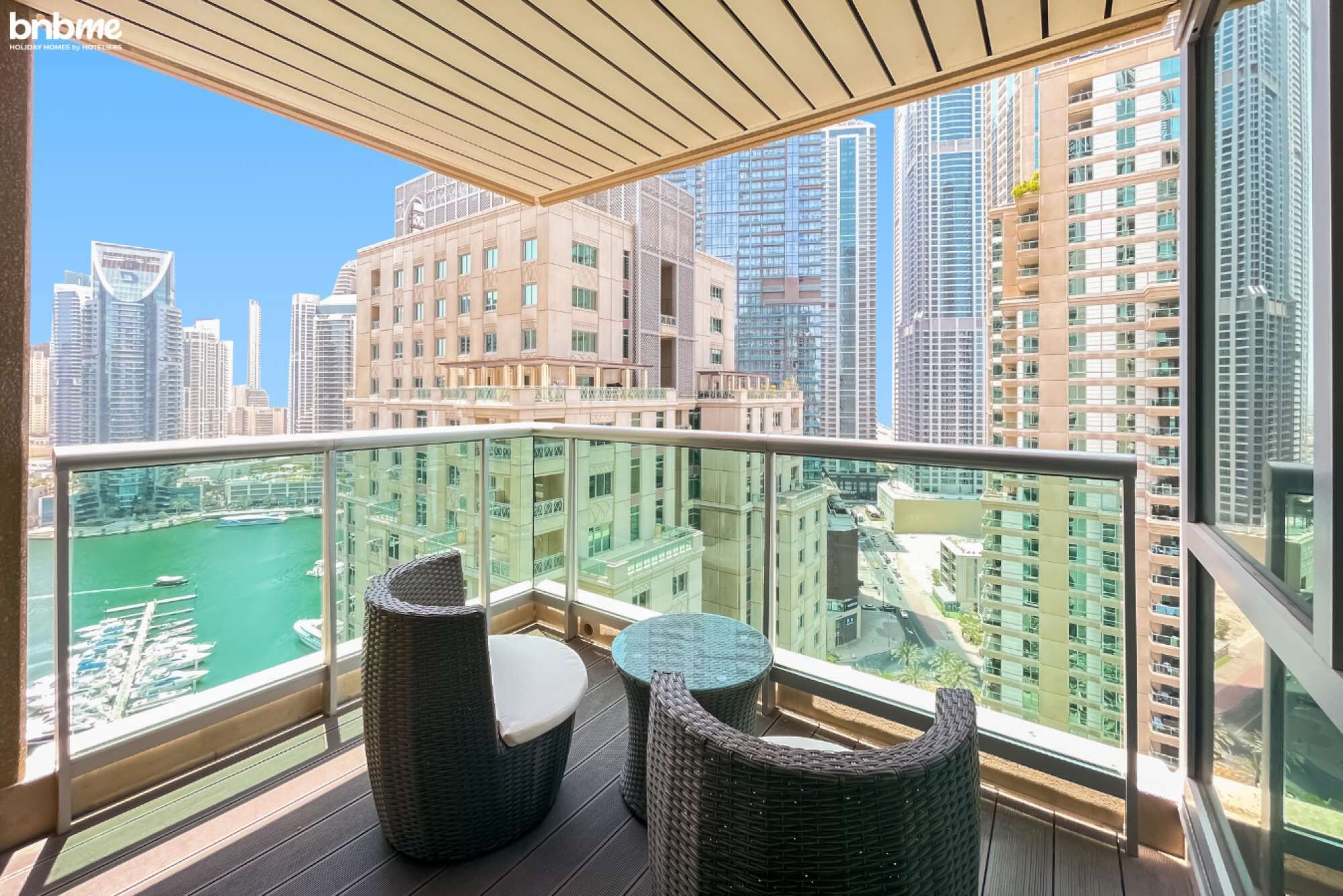 A balcony with wicker furniture and a view of a cityscape and marina.
